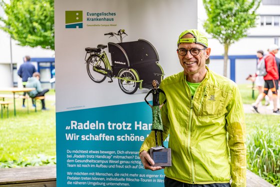  Chefarzt und Initator Dr. med. Winfried Neukäter vor dem Plakat der neuen Rikschas. 